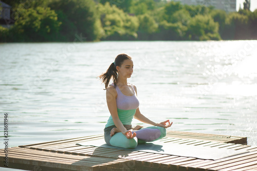 Young woman is practicing yoga at the lake © nagaets