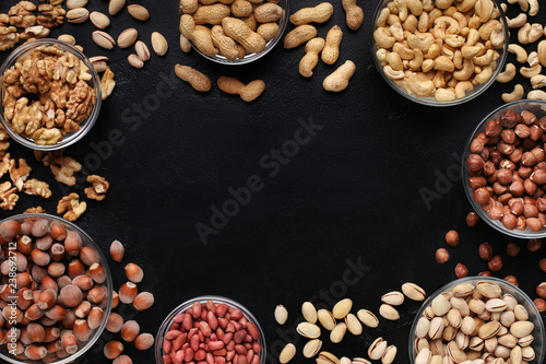 Frame of assorted nuts bowls on black background