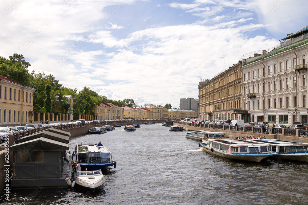 View of the Moika river from the Green bridge, St. Petersburg, Russia. Motor boats for tourists on the Moika river on a clear summer day