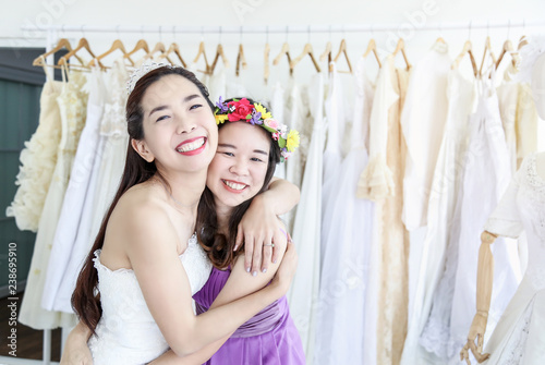 Brides and bridesmaids are hugging and smiling happily in the wedding dress shop room. © Uraiwon