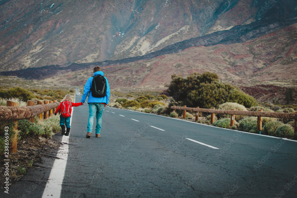 father with little daughter walking on road in mountains