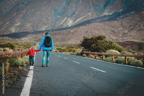 father with little daughter walking on road in mountains