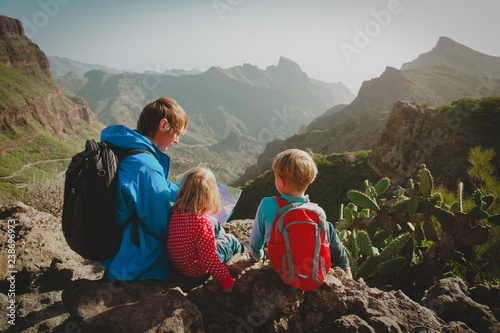 family with kids travel hiking in mountains looking at map