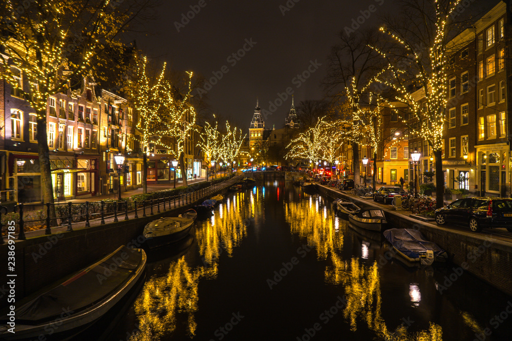 beleuchtete Gracht mit Booten in Amsterdam bei Nacht