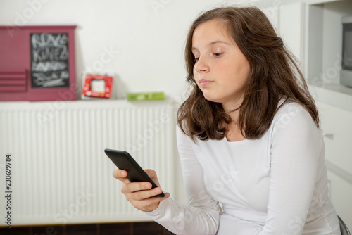 teenage girl using smartphone in the kitchen