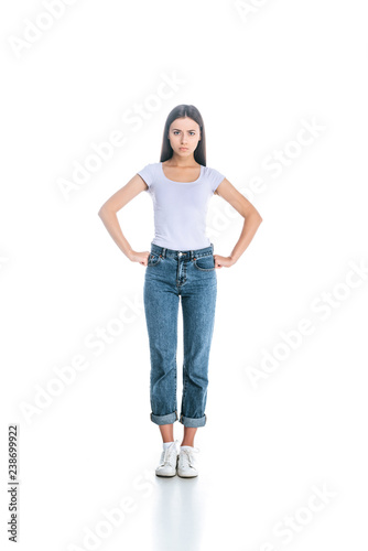 serious woman in stylish clothing standing akimbo isolated on white