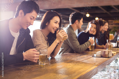 Happy friends drinking beer and talking in bar