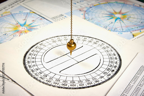 Astrological pendulum for tarot and astrological circle on the background of astrological charts and horoscopes photo