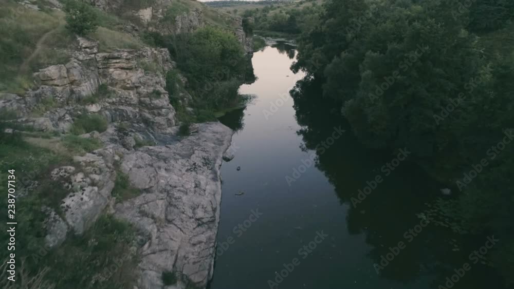 Thin stream stretching between two stony hills in the evening in summer Thin stream stretching between two stony hills in the evening in summer