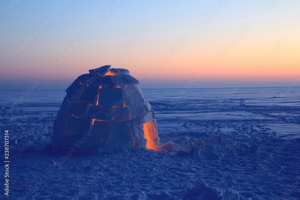 A snowy house called an igloo at sunset. - obrazy, fototapety, plakaty 