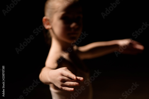 Very young ballerina posing on a black background