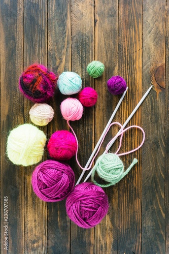 Multi-colored balls of yarn for knitting in the wooden background.