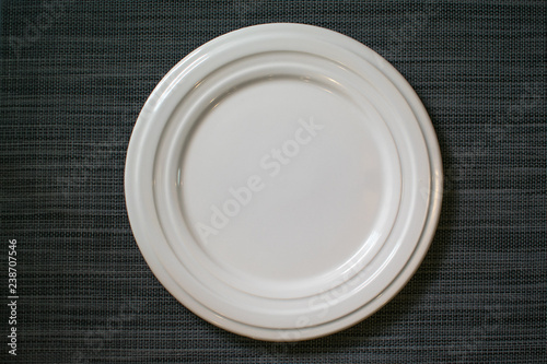 Top view of blank white plate on grey tablecloth