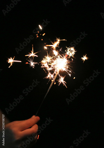 Close-up child hand holding fire sparklers on the dark at festival.