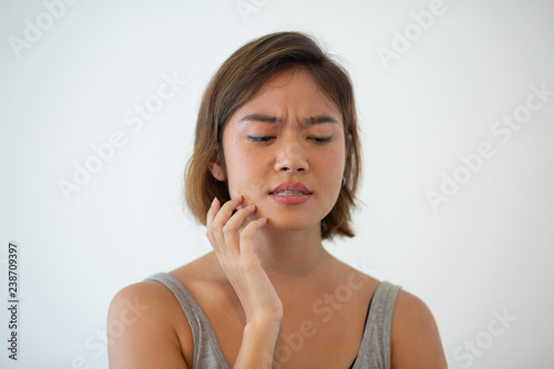 Worried pretty Asian woman touching cheek. Young lady having toothache. Dental care concept. Isolated view on white background.