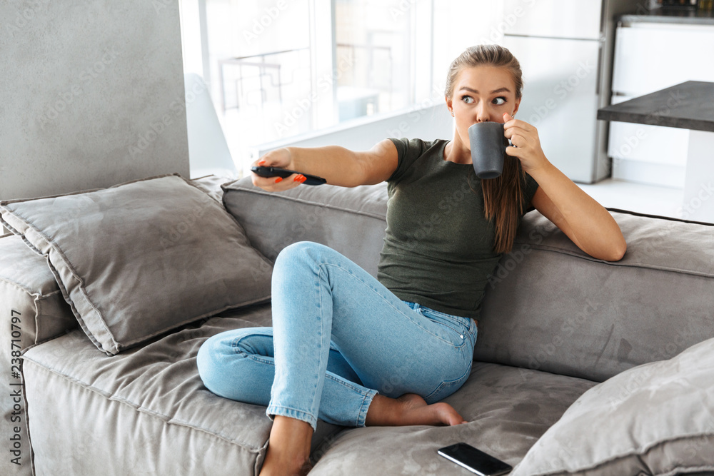 Obraz premium Cheerful young woman sitting on a couch at home