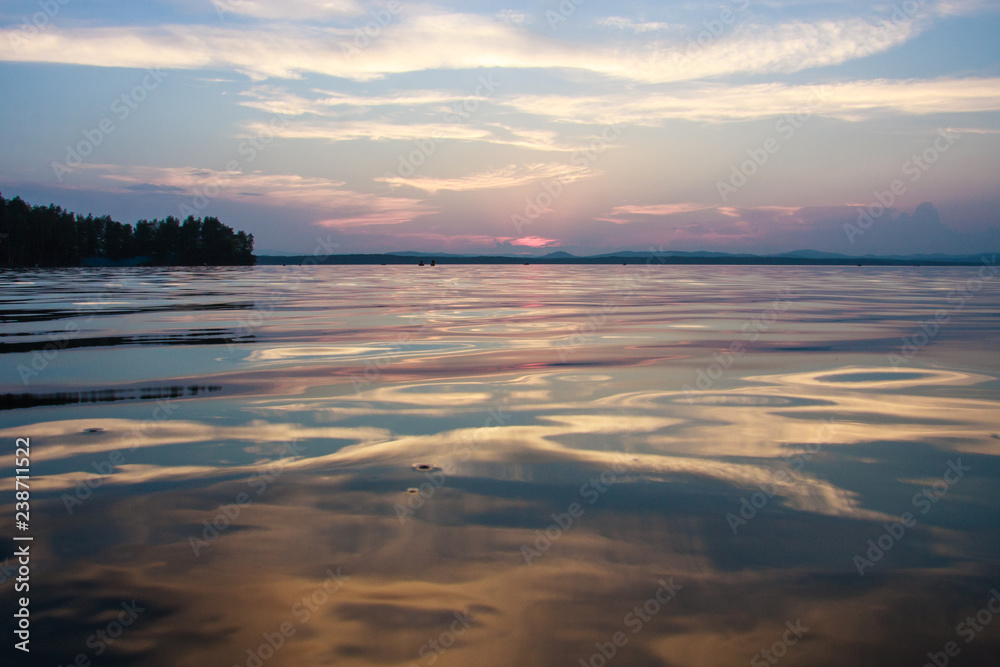 Obraz premium very beautiful sunset on the lake. beautiful natural background. blue and pink clouds with reflection from water.