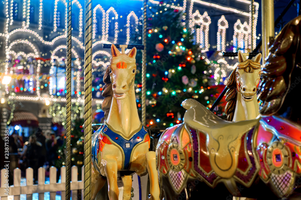 Colorful carousel before Christmas on the Red square of the Kremlin. Fabulous, night lighting, walking people.