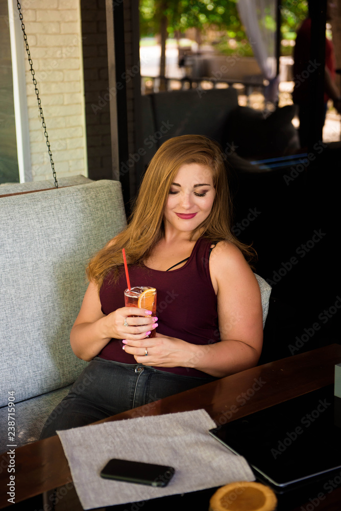 A woman of plus size enjoying life, drinking lemonade. A young lady with natural beauty. XXL model.