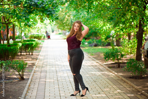 Plus size fashion model in casual clothes, overweight female body in a park outdoors.