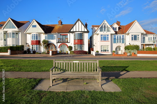 Obraz na płótnie A row of colorful houses, located on Marine Parade, with a wooden bench in the foreground, Leigh on Sea, UK w salonie