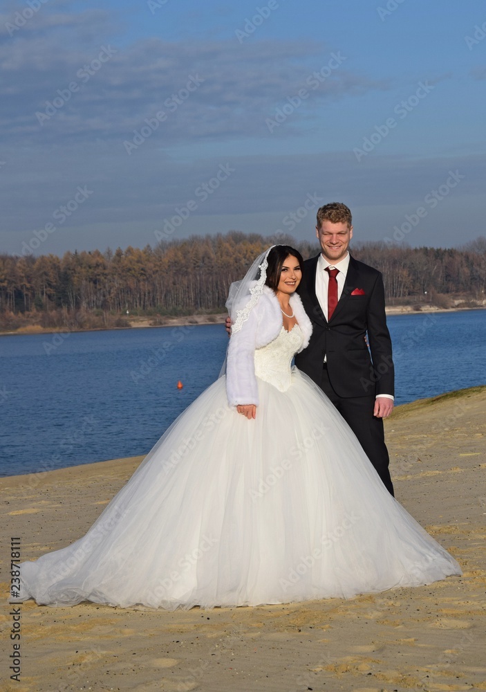 Braut und Bräutigam in festlicher Kleidung an einem Strand bei blauem Himmel im Sommer