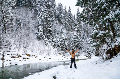 naked tempered man near a frozen river in winter forest in the mountains