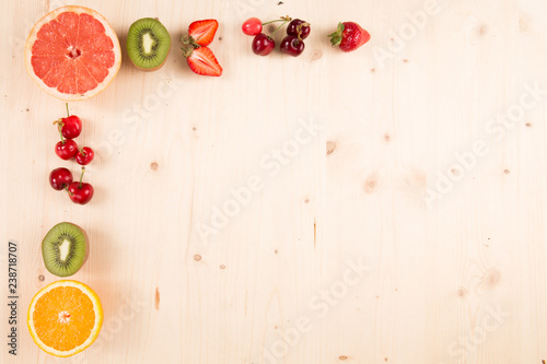 wooden background with in the fruit corner open as orange kiwi grapefruit cherry and strawberry