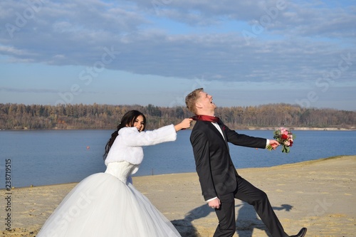 Braut und Bräutigam in festlicher Kleidung an einem Strand bei blauem Himmel im Sommer