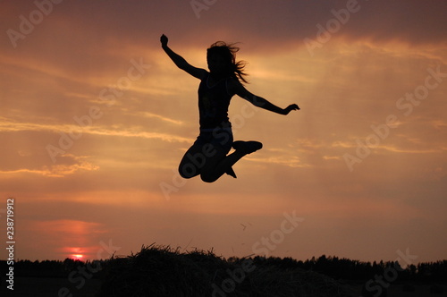 silhouette of young woman jumping in sunset