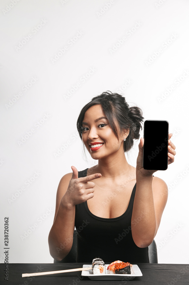 Smiling young asian woman eating sushi at the table Smiling young asian woman eating sushi at the table