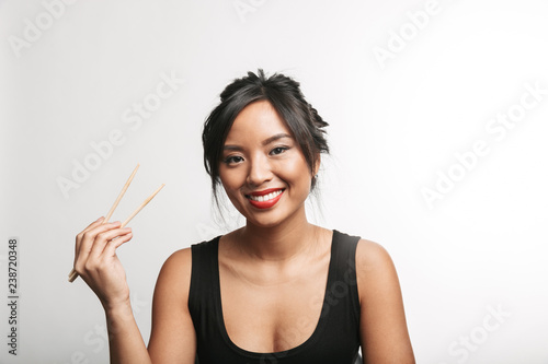Cheerful young asian woman holding chopsticks