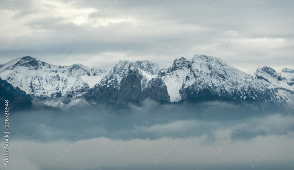 The snow capped mountain peaks of central Switzerland emerge above the clouds along the shores of the Upper Zurich Lake (Obersee), near Rapperswil-Jona, Sankt Gallen, Switzerland