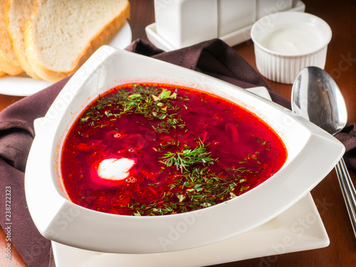 Ucrainian russian traditional beetroot soup - borsch in triangular white plate on dark brown wooden table in restaurant photo
