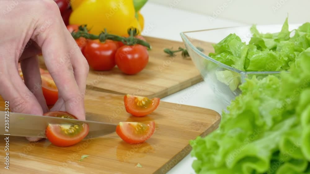 Healthy food. Vegetarian food. A man cuts a fresh tomatoes for salad Healthy food. Vegetarian food. A man cuts a fresh tomatoes for salad