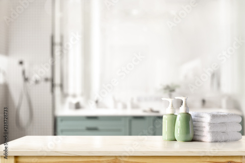 Ceramic shampoo, soap bottle and towels on counter over bathroom background. table top and copy space photo