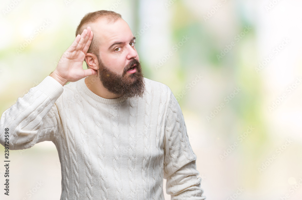 Young caucasian hipster man wearing winter sweater over isolated background smiling with hand over ear listening an hearing to rumor or gossip. Deafness concept. Young caucasian hipster man wearing winter sweater over isolated background smiling with hand over ear listening an hearing to rumor or gossip. Deafness concept.
