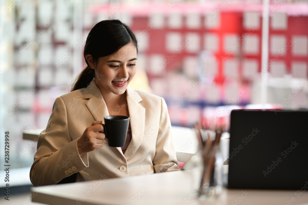 Cropped shot of a young businesswoman sitting at her desk in an office reading report on tablet Cropped shot of a young businesswoman sitting at her desk in an office reading report on tablet