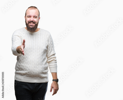 Young caucasian hipster man wearing winter sweater over isolated background smiling friendly offering handshake as greeting and welcoming. Successful business.