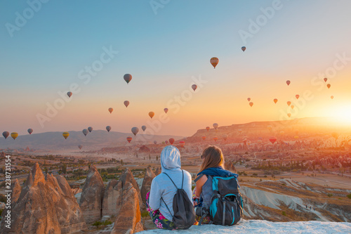 Balon na ogrzane powietrze lecący nad spektakularną Kapadocją - Dziewczyny oglądają balon na gorące powietrze na wzgórzu Kapadocji
