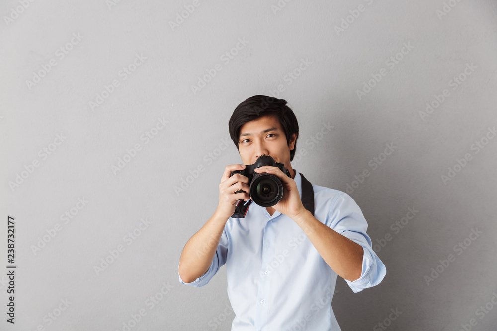 Happy asian man standing isolated over gray Happy asian man standing isolated over gray