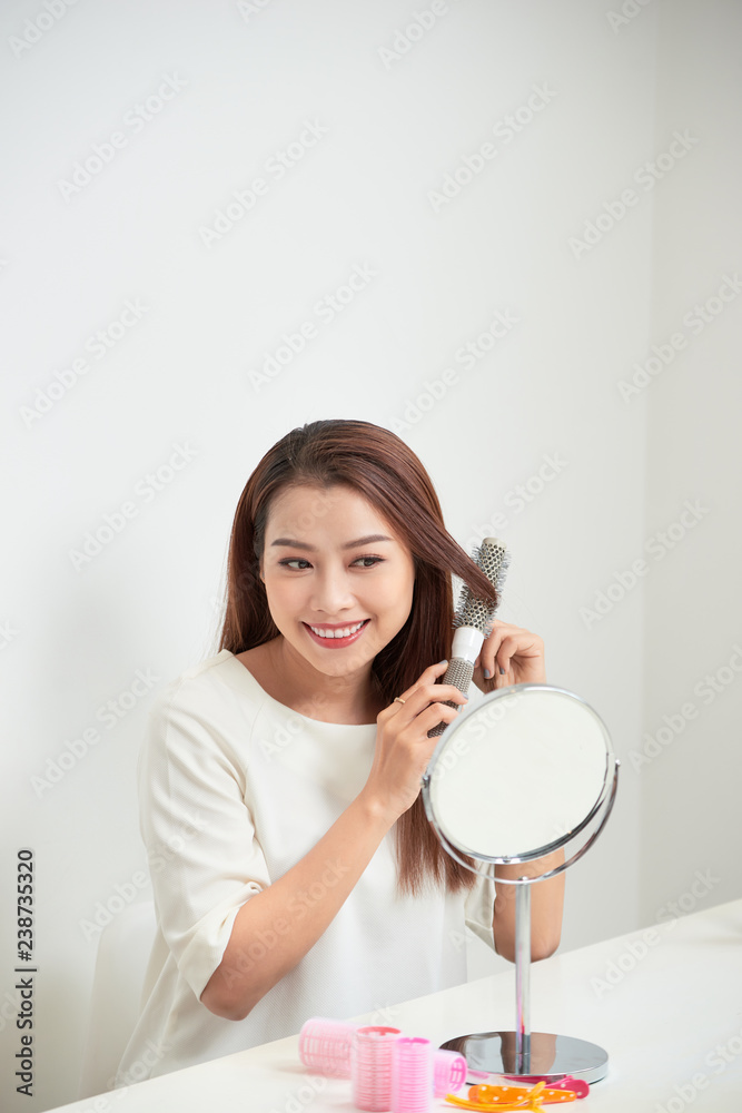 Getting rid of tangles. Beautiful young woman looking at her reflection in mirrorand brushing her long hair while sitting at the dressing table Getting rid of tangles. Beautiful young woman looking at her reflection in mirrorand brushing her long hair while sitting at the dressing table
