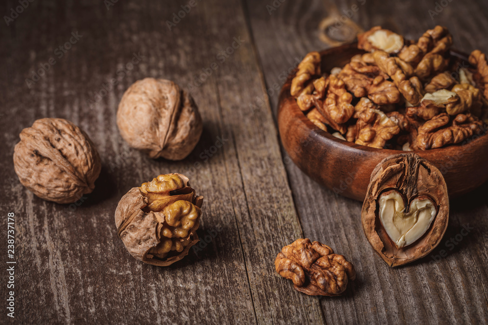 close up view of walnuts in bowl on wooden surface close up view of walnuts in bowl on wooden surface