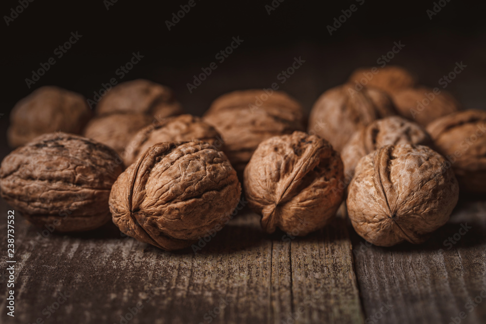 close up view of walnuts on wooden tabletop on black backdrop close up view of walnuts on wooden tabletop on black backdrop