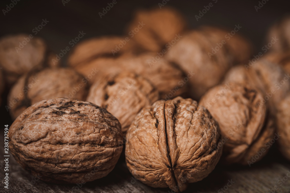 close up view of walnuts on wooden tabletop on black backdrop close up view of walnuts on wooden tabletop on black backdrop