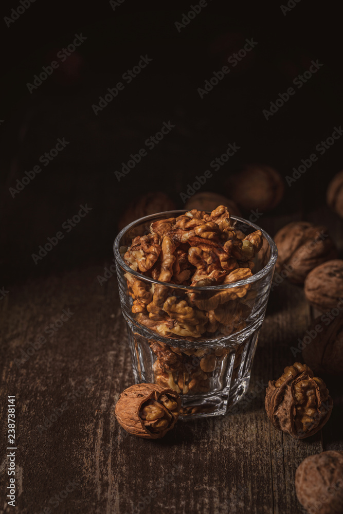 close up view of shelled walnuts in glass on wooden surface close up view of shelled walnuts in glass on wooden surface