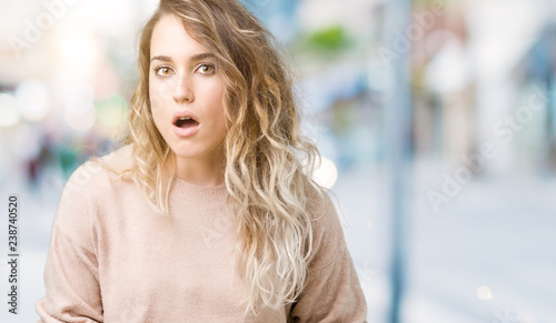 Beautiful young blonde woman wearing sweatershirt over isolated background In shock face  looking skeptical and sarcastic  surprised with open mouth