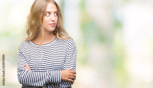 Beautiful young blonde woman wearing stripes sweater over isolated background smiling looking side and staring away thinking. © Krakenimages.com