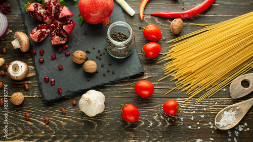 Cuisine, background of vegan food, avocado, pomegranate, mushrooms, garlic, nuts, greens and Italian spaghetti and cherry tomatoes. Clean and healthy food, detox, sports and diet