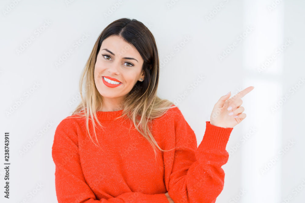 Young woman wearing casual red sweater over isolated background Pointing with hand finger to the side showing advertisement, serious and calm face Young woman wearing casual red sweater over isolated background Pointing with hand finger to the side showing advertisement, serious and calm face